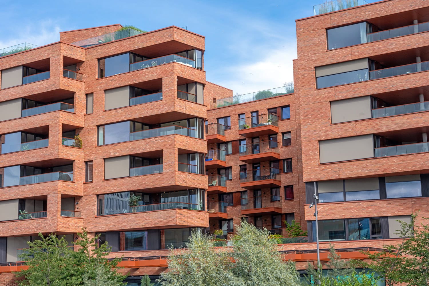 Edificio residencial de ladrillo con balcones y ventanas de gran tamaño.
