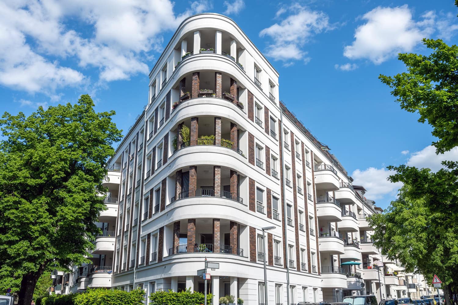 Edificio residencial moderno con varias plantas y balcones en una ciudad soleada